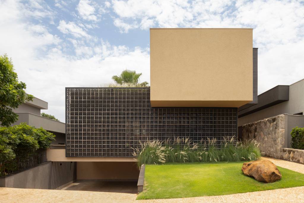 Casa moderna tem pedras rústicas de granito amarelo e cobogós na fachada