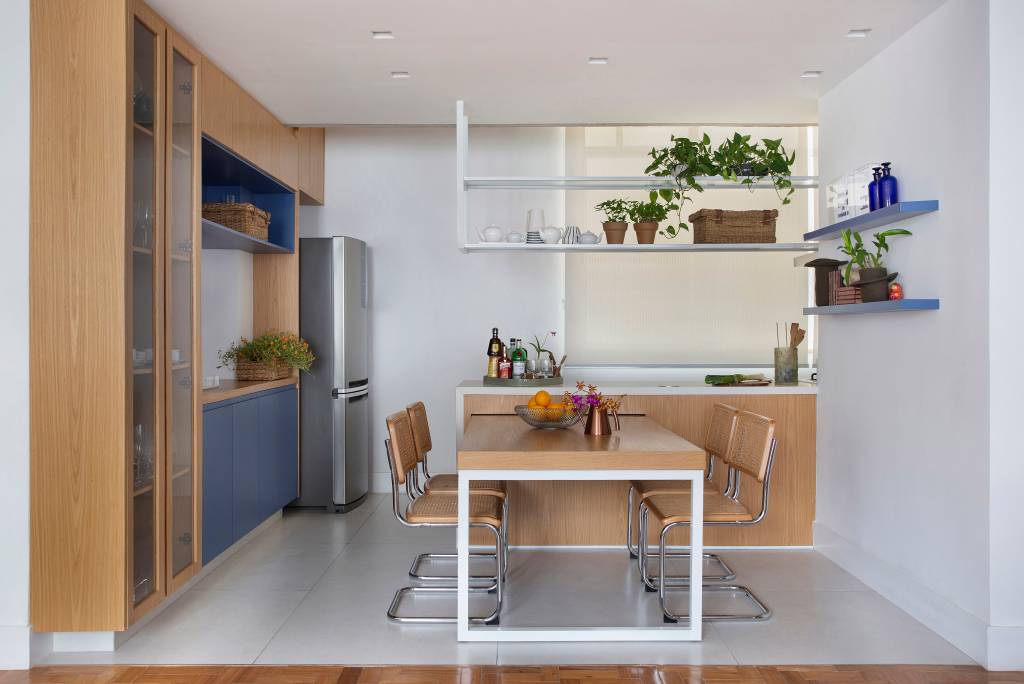 Azulejos azuis e prateleiras de vidro canelado são destaques na cozinha de apê. Projeto de Studio Duas Arquitetura.