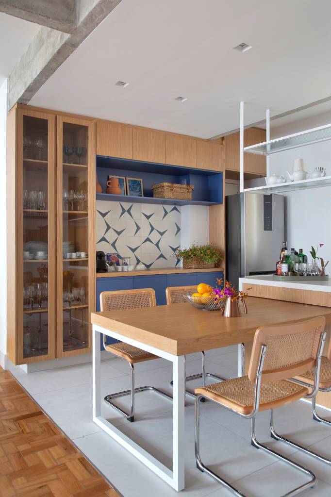 Azulejos azuis e prateleiras de vidro canelado são destaques na cozinha de apê. Projeto de Studio Duas Arquitetura.