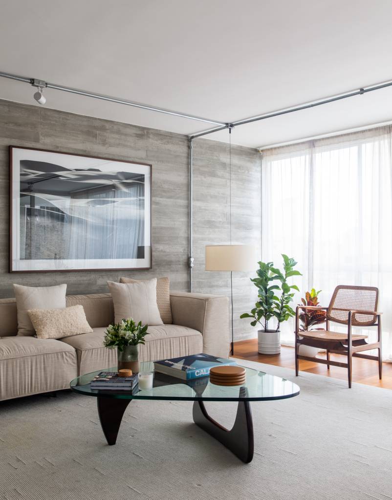 Neste apê, estante metálica branca é divisória e floreira para jiboias e costelas-de-adão. Projeto de Península Arquitetura.