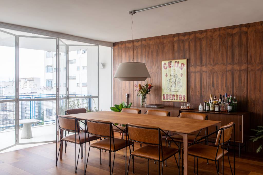 Neste apê, estante metálica branca é divisória e floreira para jiboias e costelas-de-adão. Projeto de Península Arquitetura.