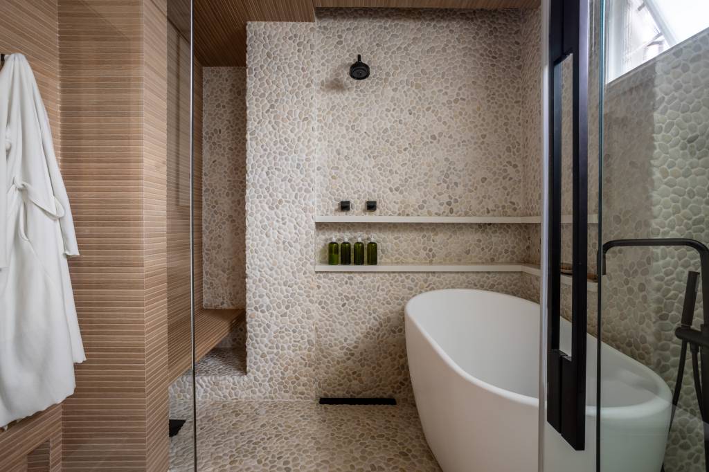 Apartamento no Jardim Europa ganha alma de casa após reforma. Projeto de Nicole Finkel. Banheiro casal com banheira e pedras na parede.