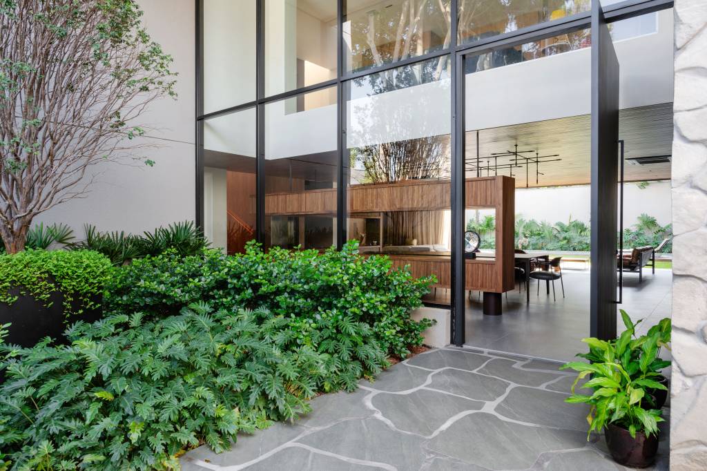 Casa de 880m² em São Paulo se integra ao jardim após ampla reforma. Projeto de Studio DWG. Fachada de vidro.