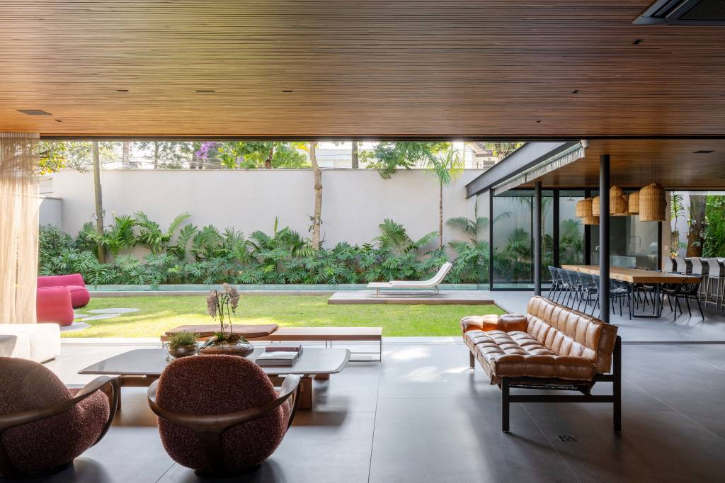 Casa de 880m² em São Paulo se integra ao jardim após ampla reforma. Projeto de Studio DWG. Integração entre ambientes externos e internos. Folhas de vidro.