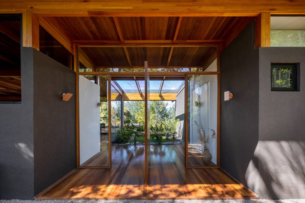 Com uso da madeira e integração com a natureza, casa térrea de 250 m² vira refúgio no interior de SP, Projeto de Sabella Arquitetura. Porta pivotante entrada.