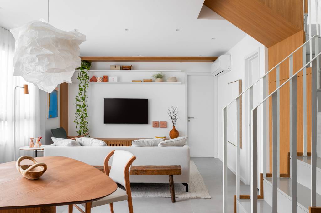 Escada de apê clean tem degraus e espelhos revestidos em quartzo cinza. Projeto de Rafael Ramos.